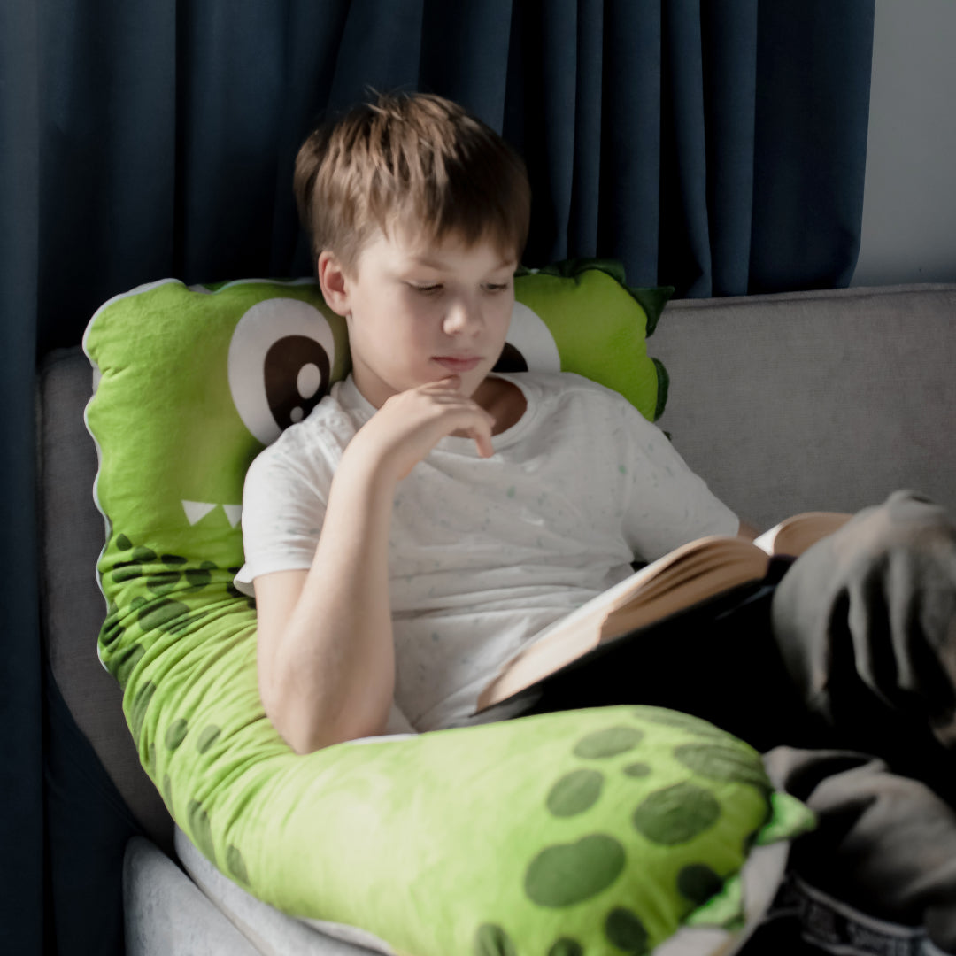 ongen leest een boek op een ZOOBY-kussen in een rustige kinderkamer.