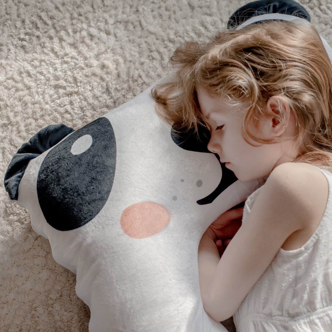 Meisje ligt op een kinderkussen met gesloten ogen en zooby knuffel, probeert rustig in slaap te vallen in een, rustige kinderkamer.