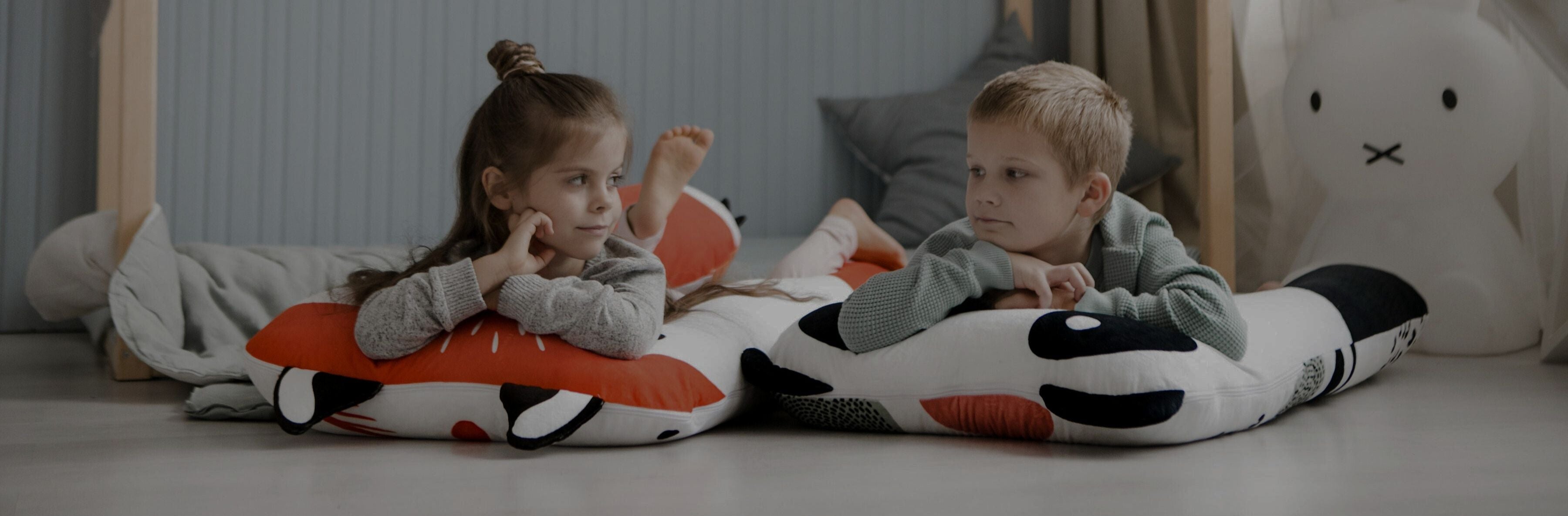 Jongen en meisje liggen comfortabel op een u-vormig kinderkussen – rust en slaap voor kinderen