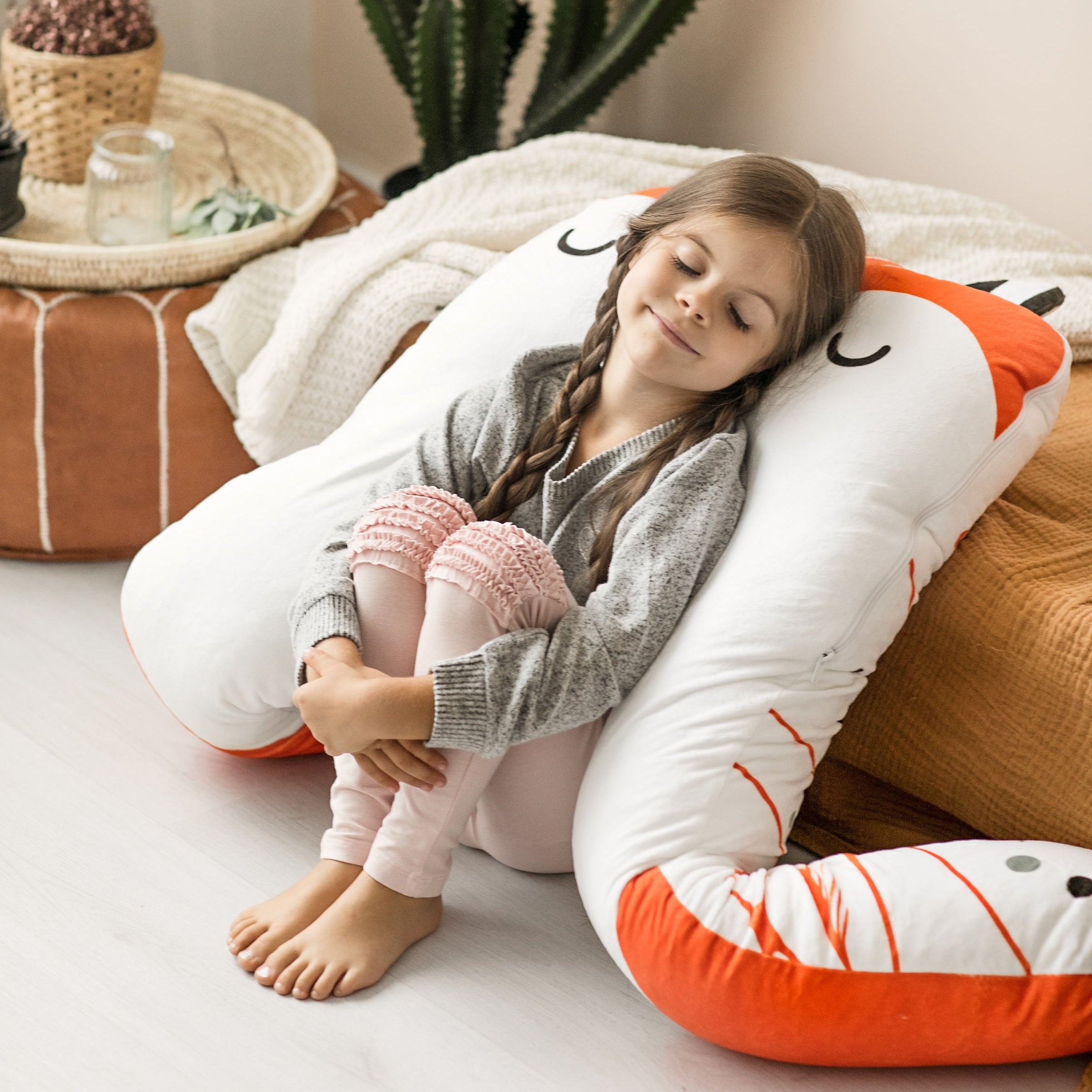 Meisje ligt comfortabel op een vosvormig kussen – rust en slaap voor kinderen